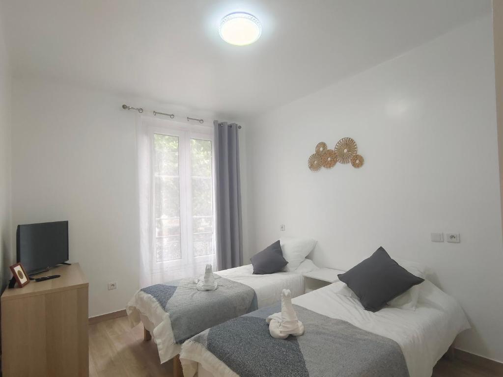 Cette chambre blanche dispose de 2 lits et d'une télévision. dans l'établissement Belleville 10, à Paris