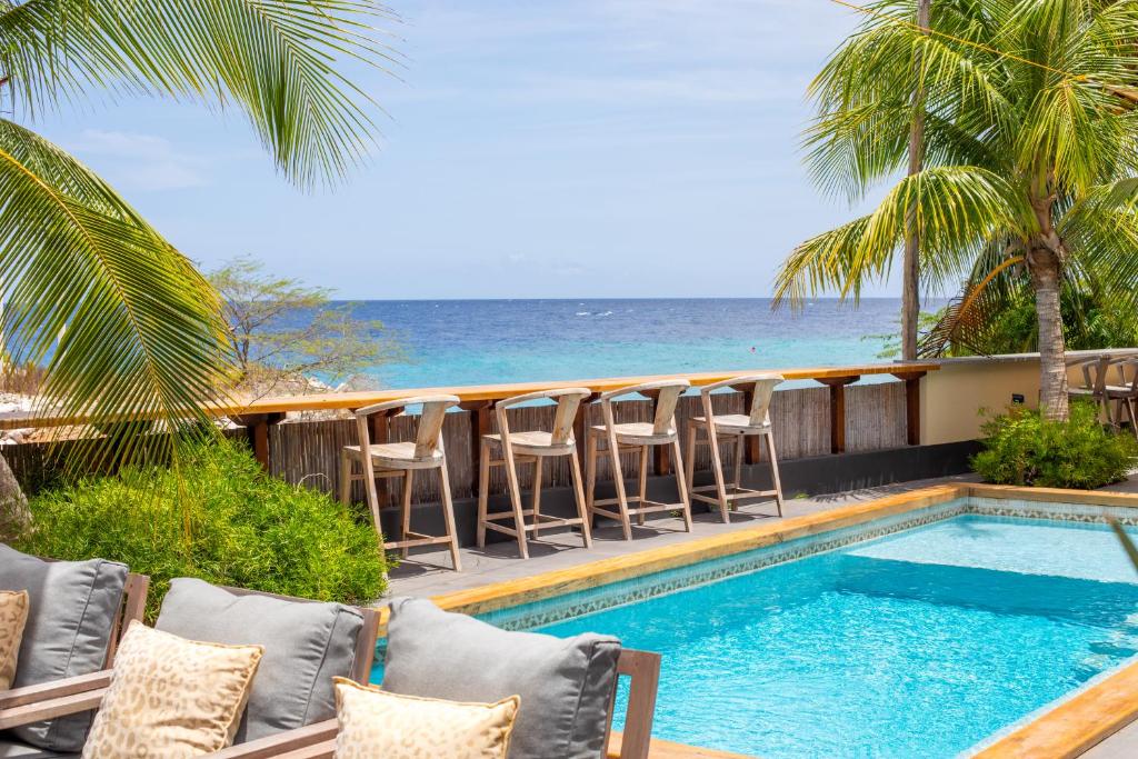 Una piscina con sillas y el océano al fondo. en Atlantis Beach House, en Willemstad