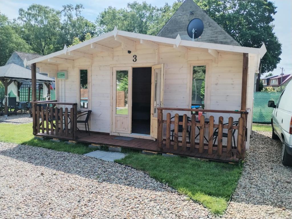 a tiny house with a porch and a fence at Słoneczna Przystań II in Wrzosowo