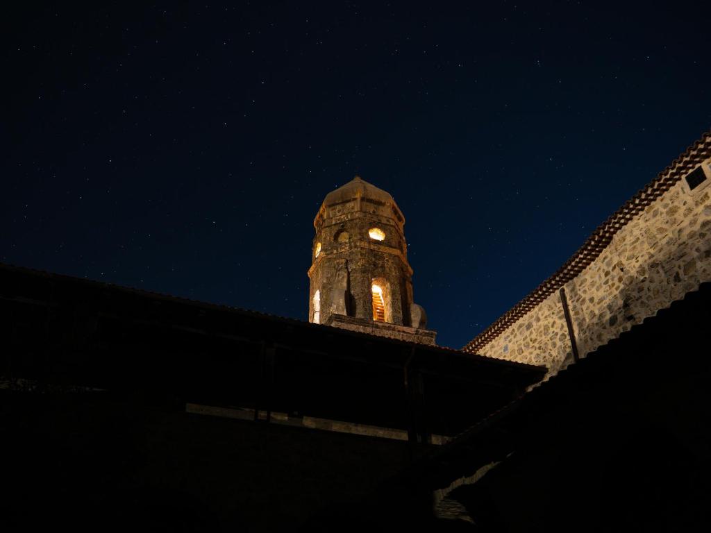 una torre de reloj en la parte superior de un edificio por la noche en Convento Francescano Experience Hotel Cilento, en Cuccaro Vetere
