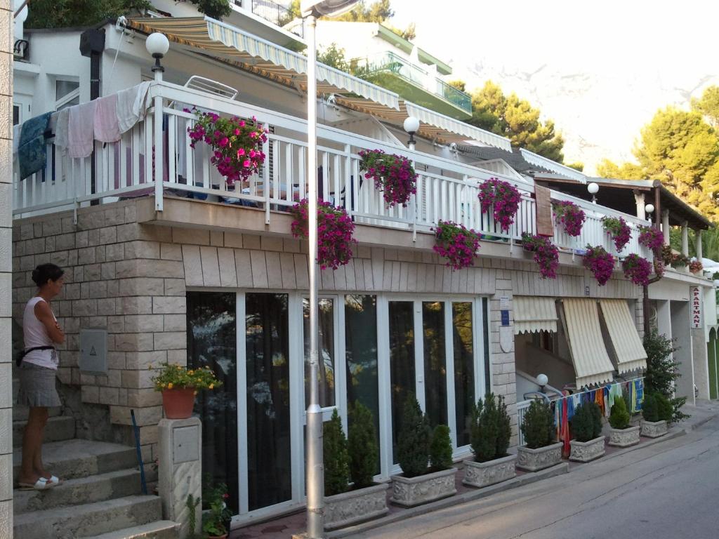 a man standing outside of a building with flowers at Apartment Herceg in Baška Voda