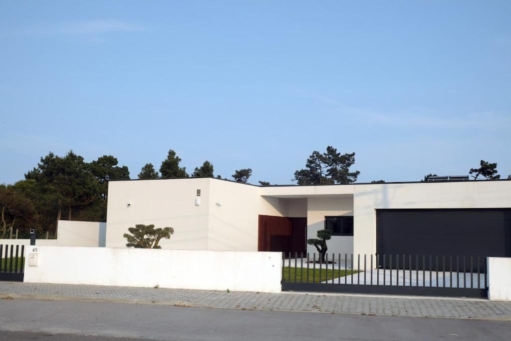 una casa bianca con una recinzione davanti di Olive House - 4 bedrooms a Gafanha da Nazaré