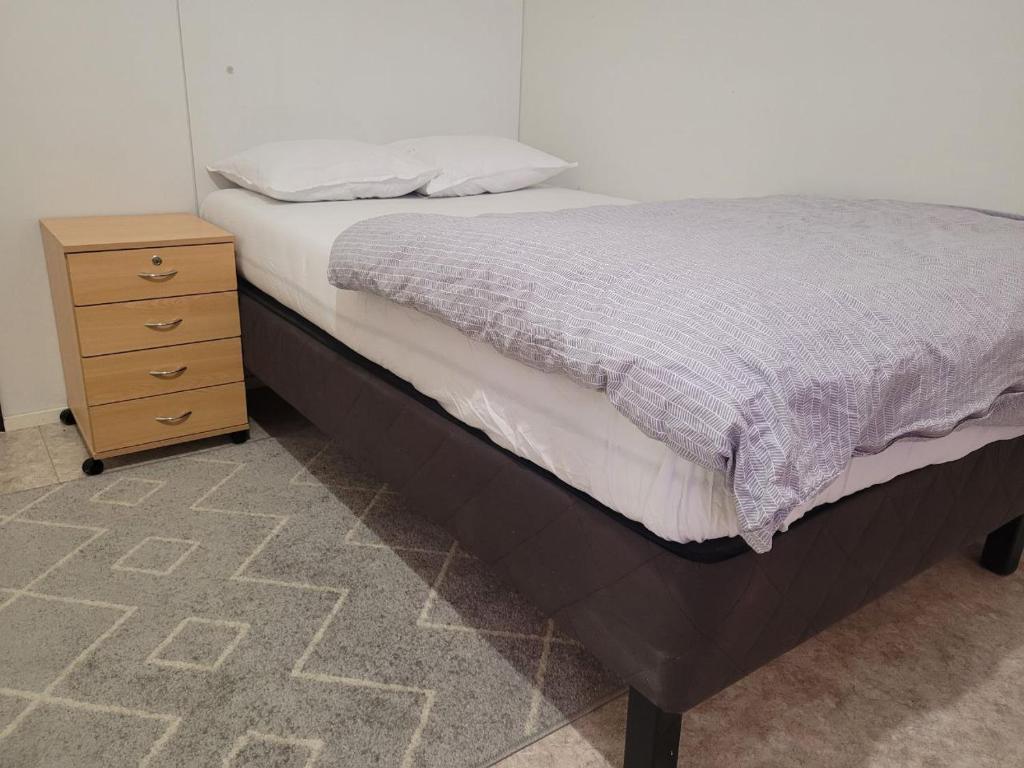 a bed with a wooden nightstand next to a bed sidx sidx sidx at Private Room in Shared Apartment in Vaasa