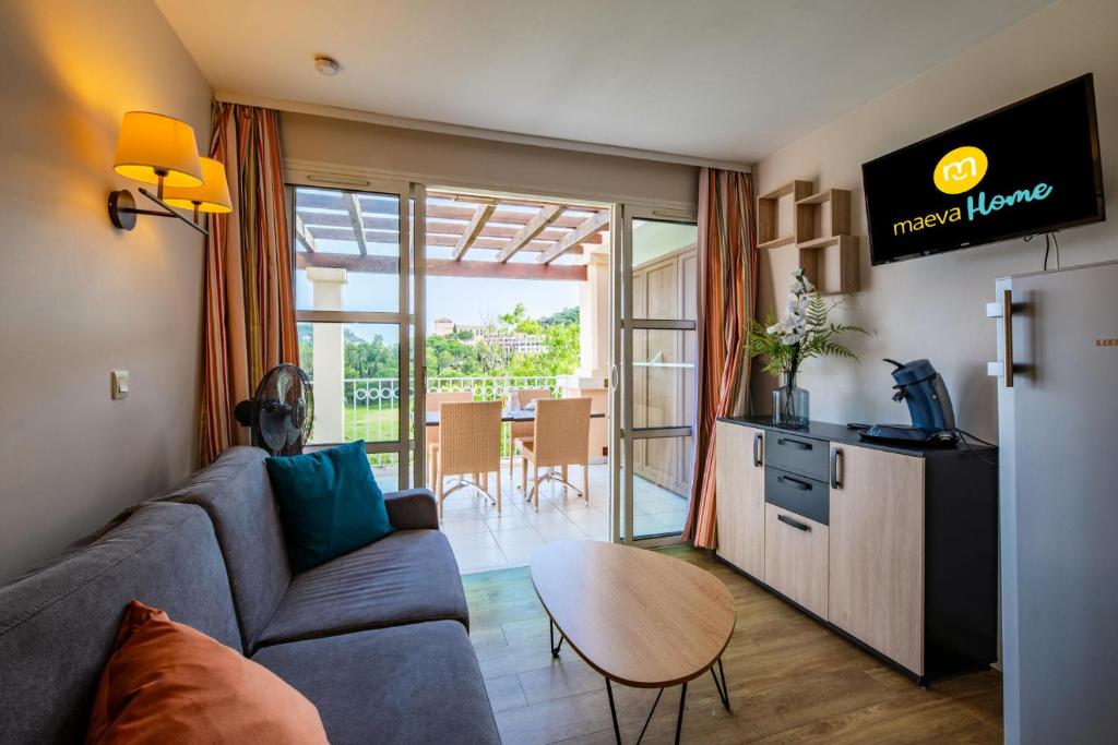 un salon avec un canapé et une table dans l'établissement Résidence le Village de Cap Esterel - maeva Home - Appartement 2 pièces 4 personnes - Sélection MAE-0810, à Saint-Raphaël
