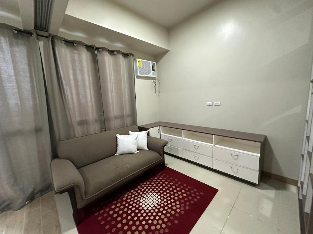 a living room with a couch and a red rug at Cozy Condo in Megaworld Iloilo in Iloilo City