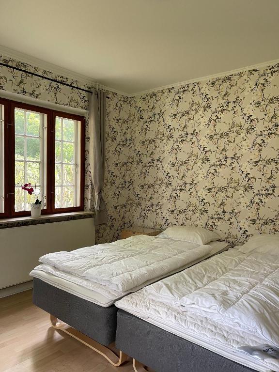 Un dormitorio con dos camas y papel pintado floral. en The Gatekeepers Cottage at Hindemae Estate Cozy Stay in Historic Surroundings, en Ullerslev