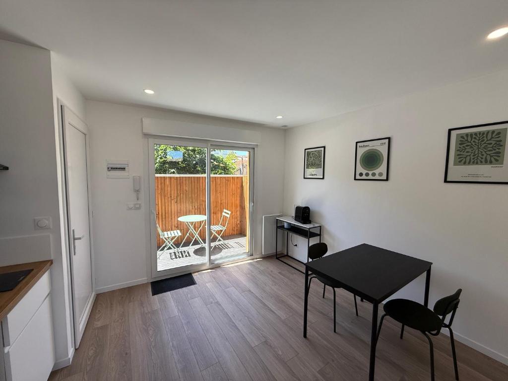 un salon avec une table et des chaises et un balcon dans l'établissement Julada Appartement, à Bègles