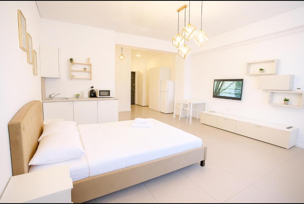 a white bedroom with a bed and a kitchen at Marina studio in Mamaia Nord