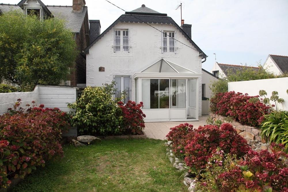 une maison blanche avec un jardin et quelques fleurs dans l'établissement Ty Albéric, plages et commerces à pied, à Trégastel
