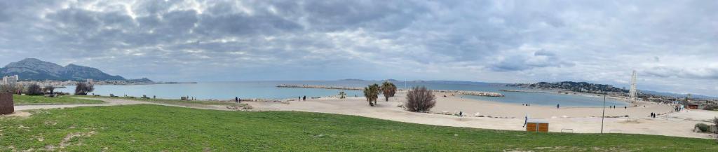 une plage avec des gens marchant sur le sable et un plan d'eau dans l'établissement Orus Corner - plage à 5 minutes à pied, à Marseille
