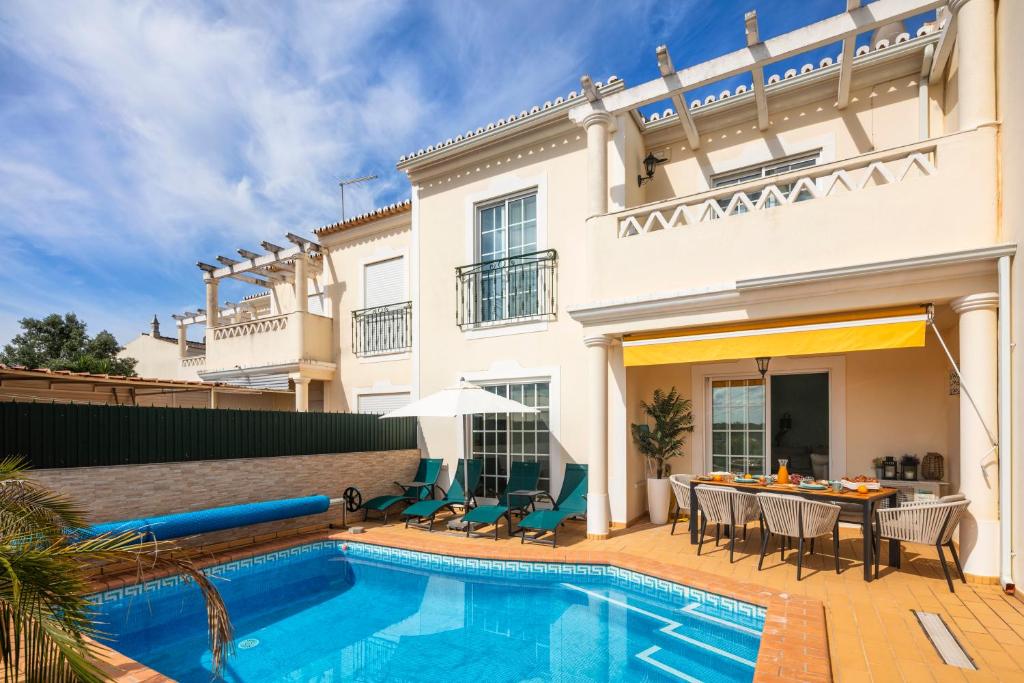 a villa with a swimming pool in front of a house at Beautiful townhouse in downtown Ferragudo in Ferragudo