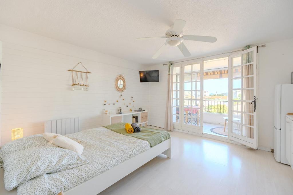 une chambre blanche avec un lit et un ventilateur de plafond dans l'établissement Studio Horizon Sablettes, à La Seyne-sur-Mer