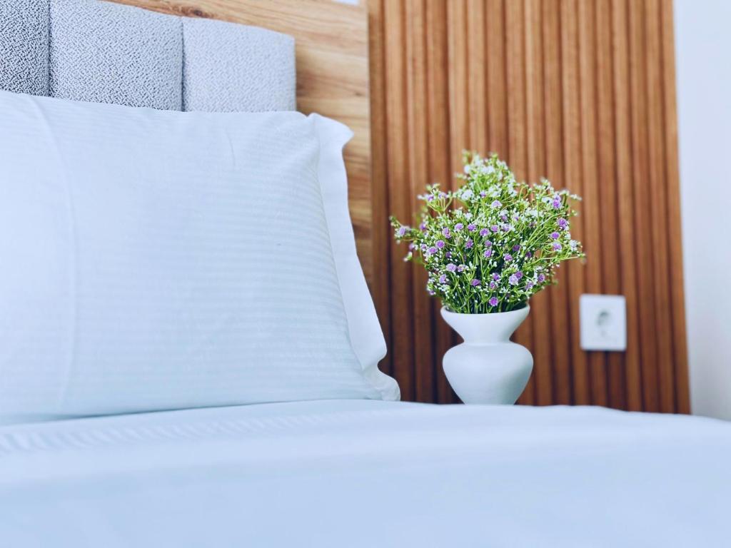 a white vase with flowers in it next to a bed at Home Side Apartment in Batumi