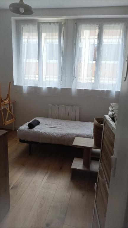- un lit dans une chambre avec 2 fenêtres dans l'établissement Agréable studio -1 personne, à Dijon