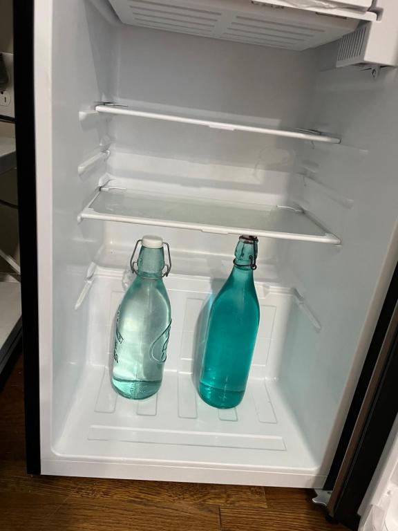 two blue glass bottles sitting inside of an open refrigerator at Near the Center of it All in Raleigh