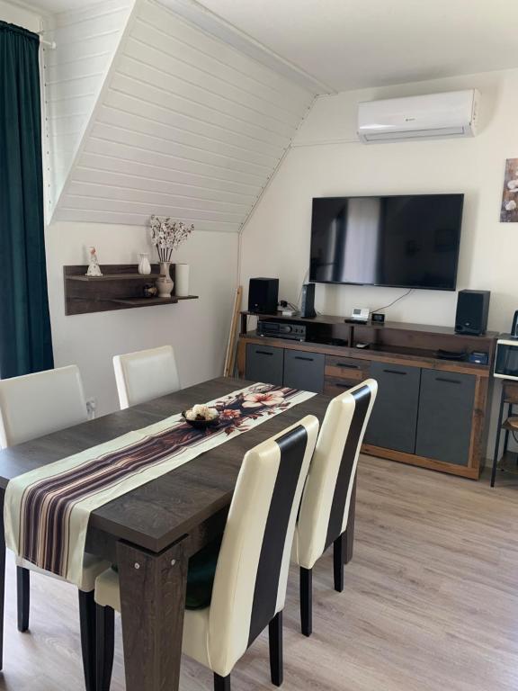 a dining room with a table and chairs and a television at Krisztina apartman in Zalakaros