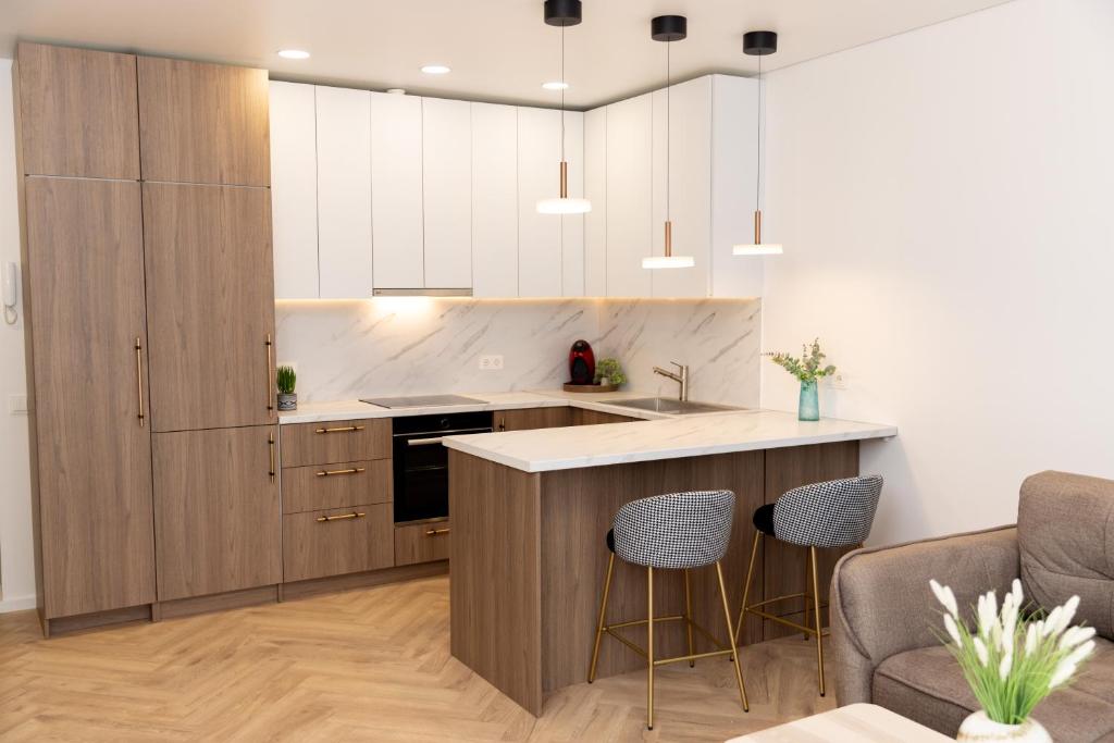 een keuken met houten kasten en een eiland met barkrukken bij Apartamentai Šilutė in Šilutė