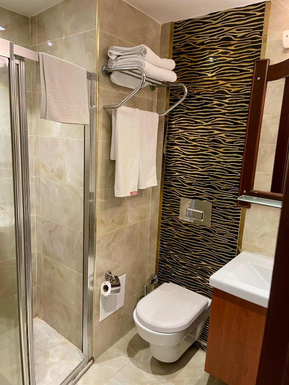 a bathroom with a shower and a toilet and towels at Istanbul Newcity Hotel in Istanbul