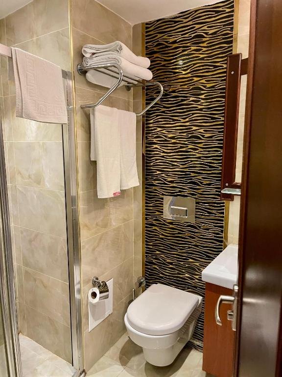 a bathroom with a shower and a toilet and towels at Istanbul Newcity Hotel in Istanbul