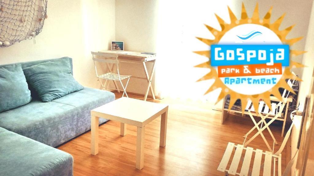 a living room with a blue couch and a sign at Gospoja Park & Beach Apartment Vrbnik in Vrbnik