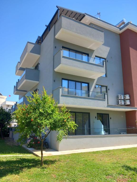 an apartment building with balconies and a tree at Hotel Ksamili in Ksamil
