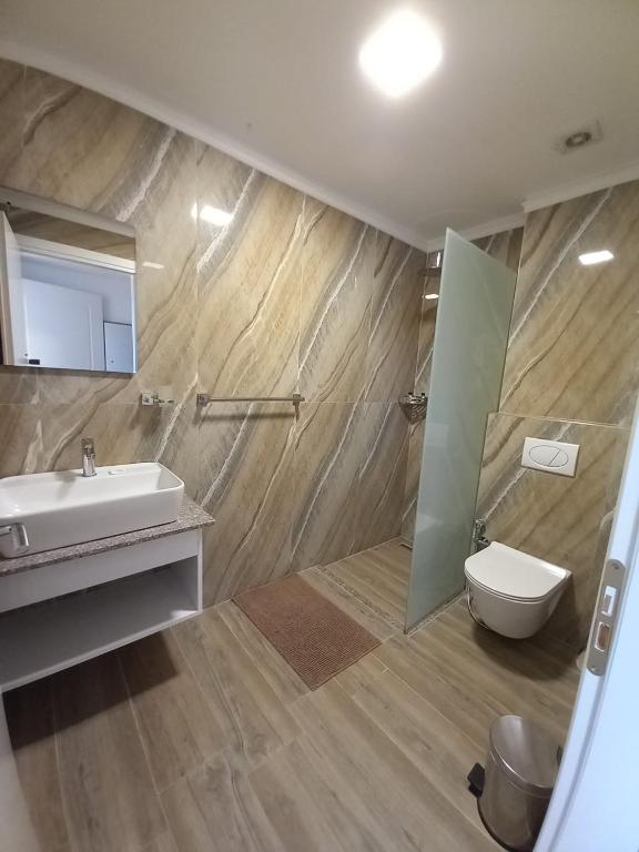 a bathroom with a sink and a toilet and a mirror at Hotel Ksamili in Ksamil