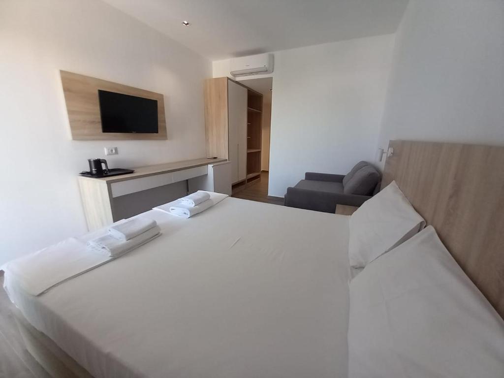 a large white bed in a room with a couch at Hotel Ksamili in Ksamil