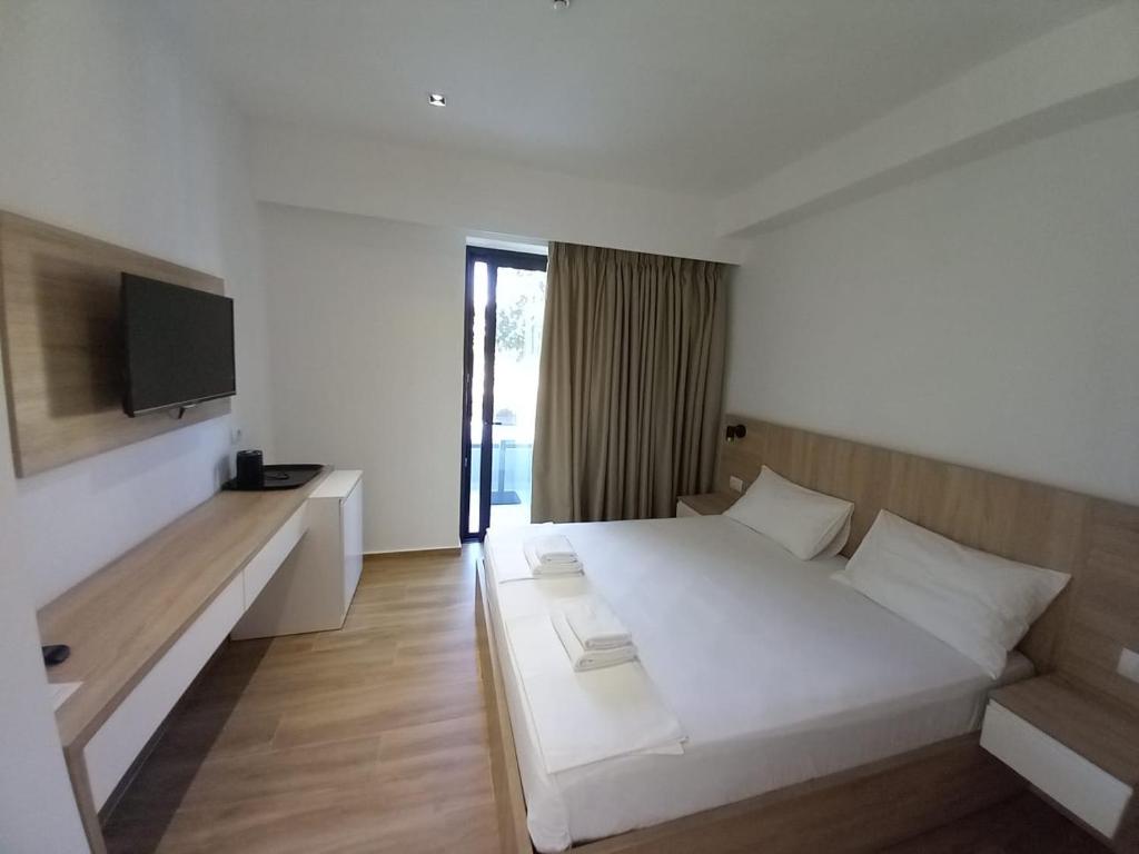 a bedroom with a white bed and a television at Hotel Ksamili in Ksamil