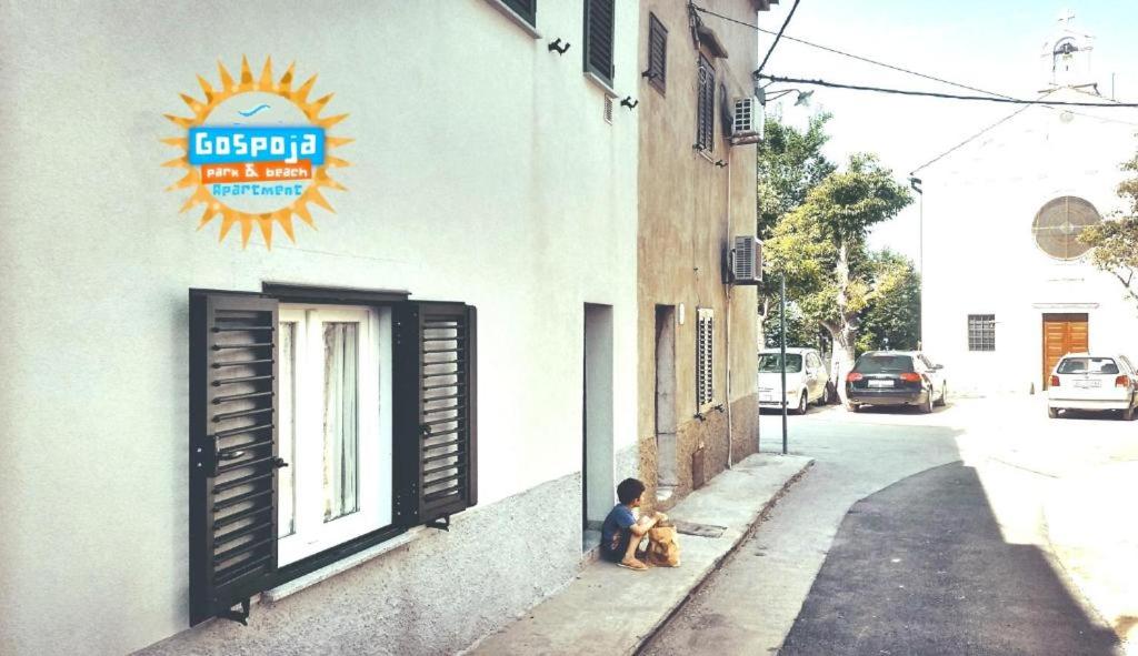 a child sitting next to a building with two teddy bears at Gospoja Park & Beach Apartment Vrbnik in Vrbnik