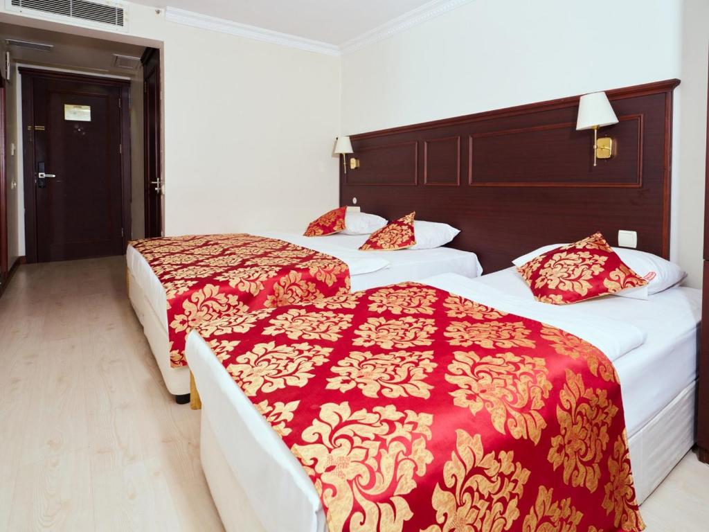 two beds in a hotel room with red and gold blankets at Istanbul Newcity Hotel in Istanbul