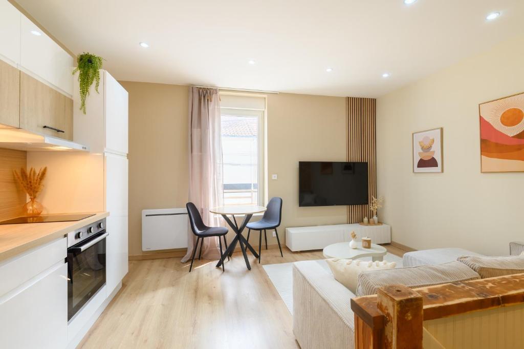 un salon avec un canapé et une table avec des chaises dans l'établissement Les Pierres dorées - Moderne & Confort, à La Roche-sur-Yon