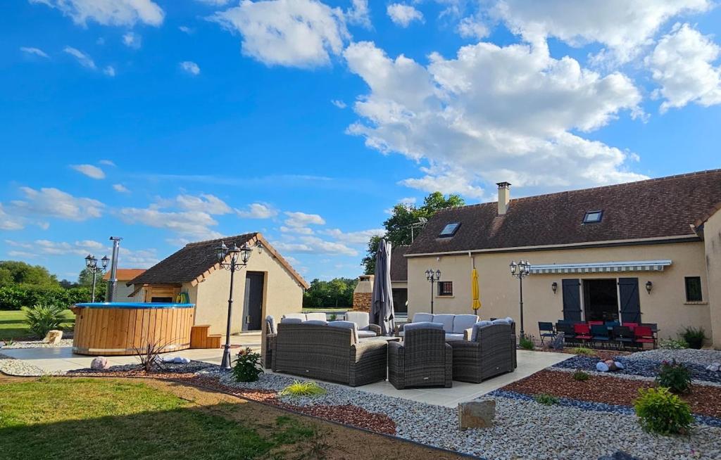 une arrière-cour avec des chaises et une maison dans l'établissement Gîte Les Chalottières - 12 pers avec bain nordique, à Changé