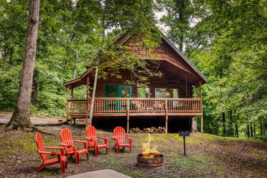 a log cabin with red chairs and a fire pit at Pine Ridge in Sevierville
