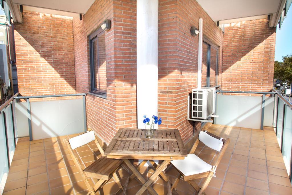 a patio with a wooden table and chairs on a balcony at New & Sunny Apartment in Barcelona