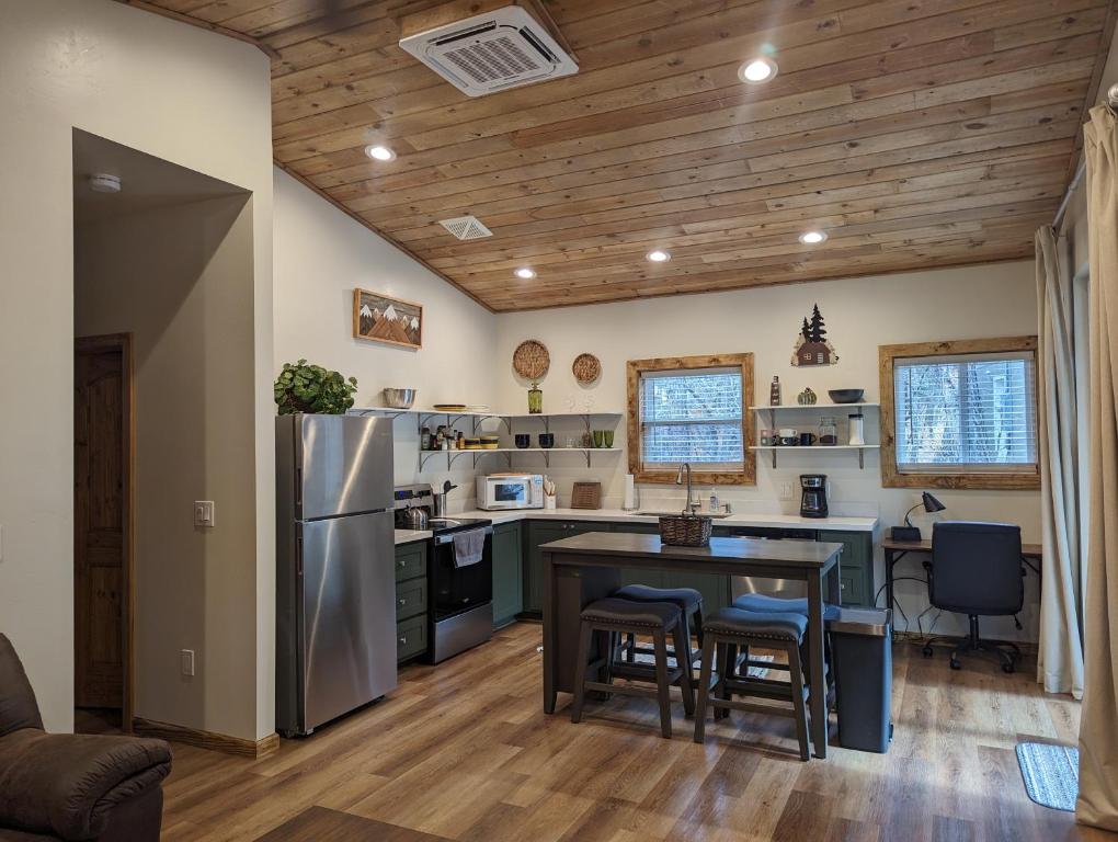a kitchen with a table and a stainless steel refrigerator at The Perfect Pair, Cozy Cottage Lakeside & Hillside Hangout for Large Groups in Pinetop-Lakeside