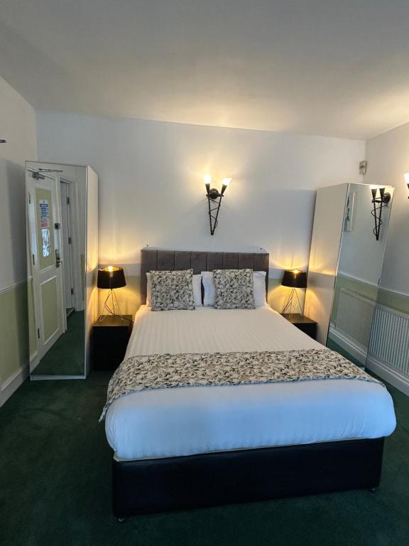 Un dormitorio con una cama grande con dos lámparas. en Barons Court Hotel, en Wolverhampton