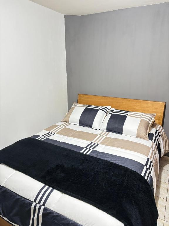 a bed with a black and white blanket on it at Room Airport in Bogotá