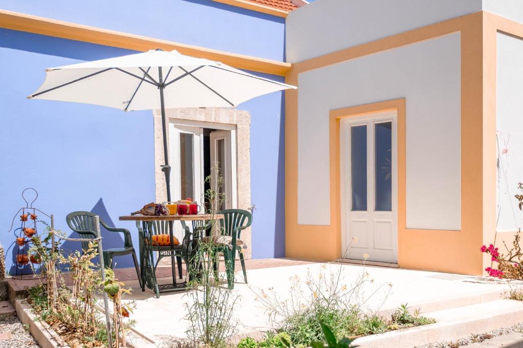 a table and chairs with an umbrella on a patio at Casinhas do Arco da Velha in Palmela