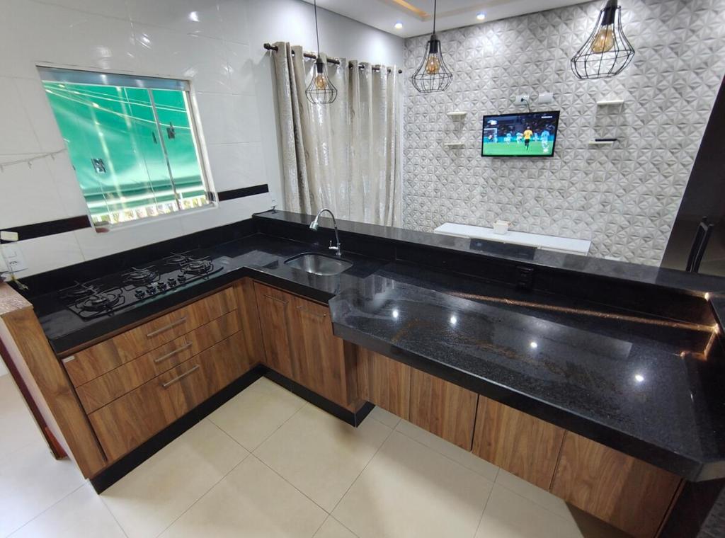 a kitchen with a sink and a tv on the wall at Apartamento charmoso in Pirassununga