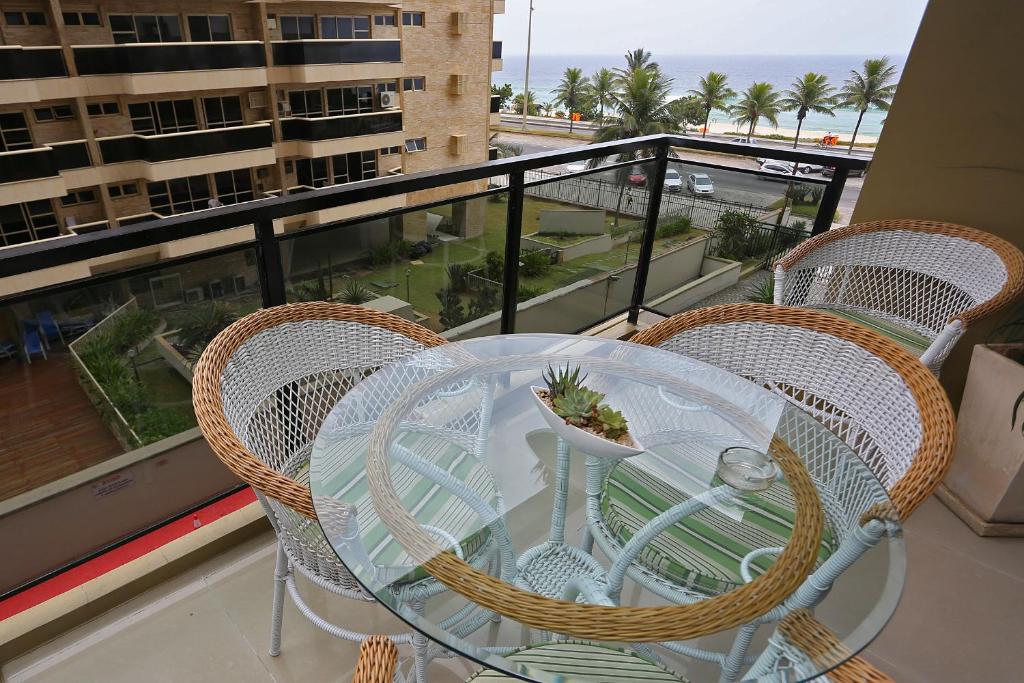 y balcón con mesa de cristal y sillas. en Barrabella Apart Hotel, en Río de Janeiro