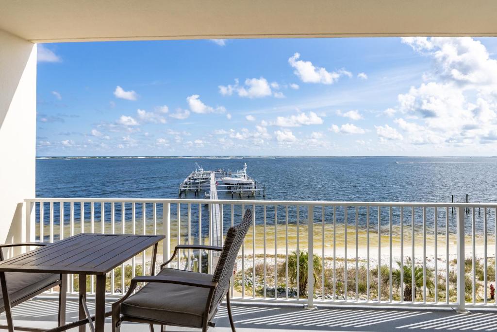 a balcony with a table and chairs and a boat in the ocean at Harbour Pointe 309 By Pkrm in Pensacola