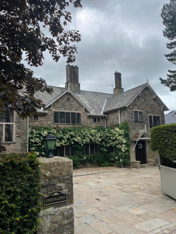 an old stone house with a sign in front of it at Greenacres Hall in Disley