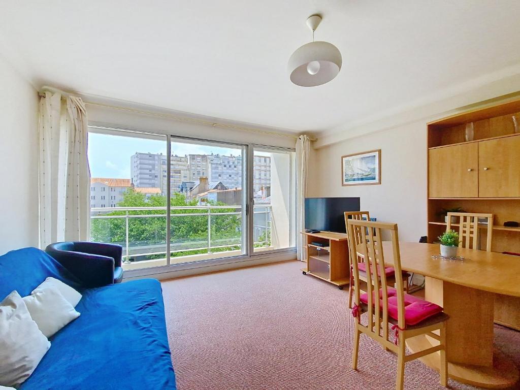 un salon avec un canapé bleu et une table dans l'établissement Appartement lumineux 2 pièces à 100 m de la plage et du marché Arago, avec balcon et parking sécurisé - FR-1-331-100, à Les Sables-dʼOlonne