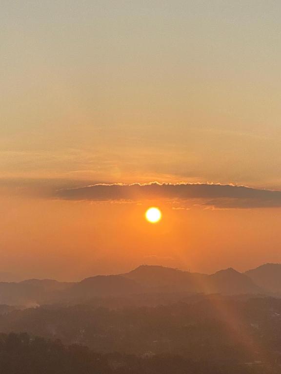 a sunset over mountains with the sun in the sky at The Space Garden Hotel Kandy in Nikawatawana