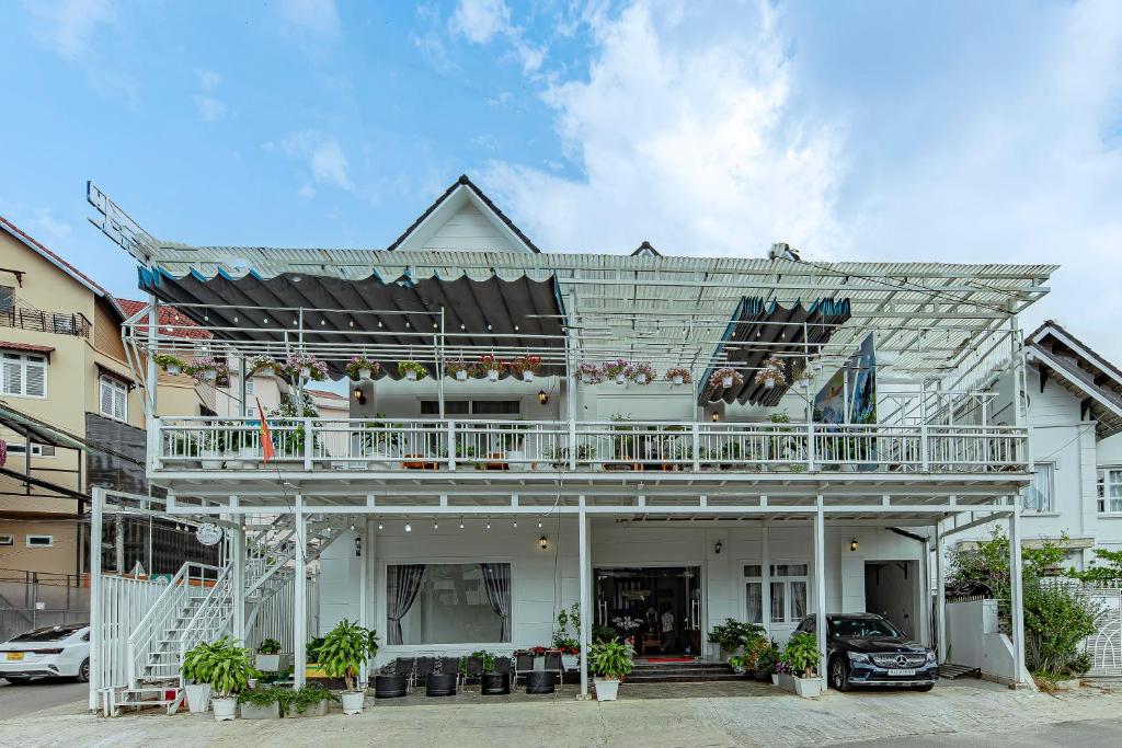 a white house with a balcony on top of it at Ngân Hà Xanh Hotel in Da Lat