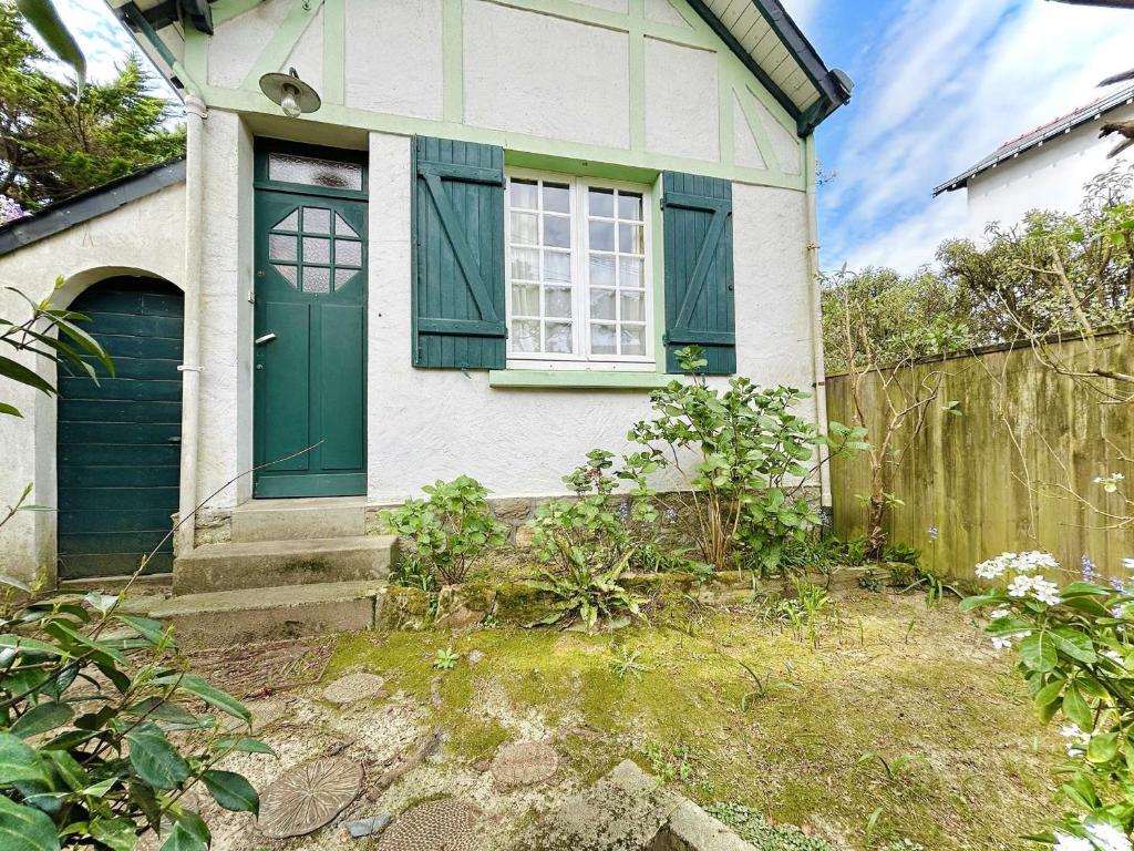 une maison avec une porte verte et une clôture dans l'établissement Maison cosy 2 pièces avec jardinet, La Baule Centre - FR-1-245-216, à La Baule
