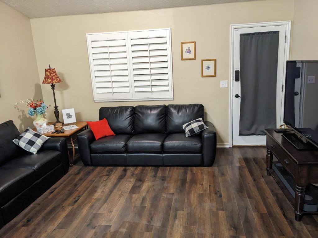 a living room with a black leather couch and a television at Beautiful Large Residential Home in Layton