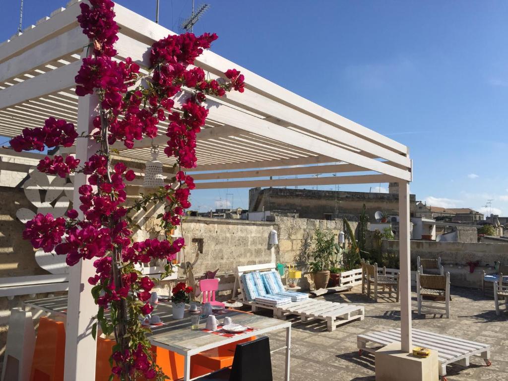 une pergola avec des fleurs roses sur une terrasse dans l'établissement B&B Le Giravolte, à Lecce