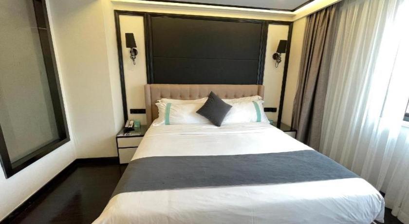 a bedroom with a large white bed with a window at Xana Hotelle Xiamen Airport Zone Government in Xiamen