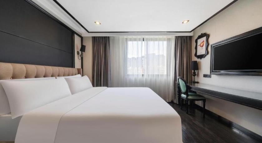 a bedroom with a large white bed and a desk at Xana Hotelle Xiamen Airport Zone Government in Xiamen